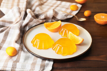 Plate with tasty orange jelly on dark wooden background