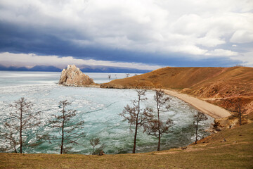 Lake Baikal in the spring, the time of ice melting. Beautiful view of Cape Burhan or Shamanka rock on Olkhon Island.