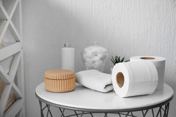 Rolls of toilet paper and bath supplies on table in bathroom