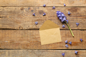 Beautiful hyacinth flower and blank envelope on wooden background