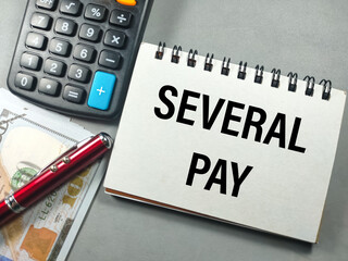 Business concept.Text SEVERAL PAY with notebook,banknote and calculator on gray background.