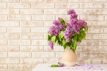 Vase with lilac flowers on table