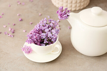 Cup with beautiful lilac flowers and teapot on light background