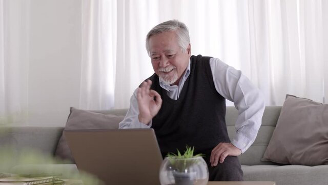 Elderly Asian man video conferent online with teblet at home.