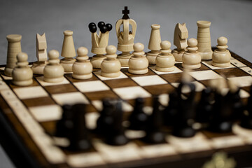 Wooden Chess pieces on board, arranged in incorrect initial position selective focus. White king is...