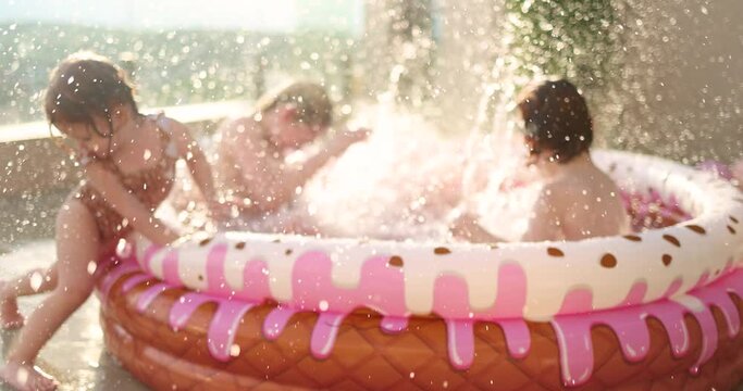 excited kids having fun, splashing water in inflatable pool at home patio, sunny summer activities