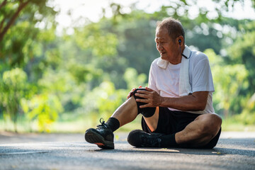 Asian Senior man suffering with knee pain during workout in the park.