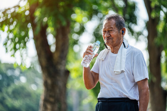 Happy thirsty senior man drinking fresh water after sports in park, Concept of senior healthy lifestyle.