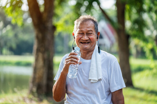 happy asian active senior asian man drinking water after exercise in park, Concept of senior healthy lifestyle.