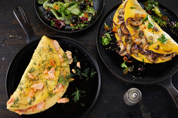 Frying pans with omelettes placed near salad