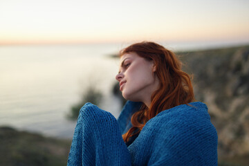 pretty woman in the mountains outdoors covered herself with a blanket coolness traveling