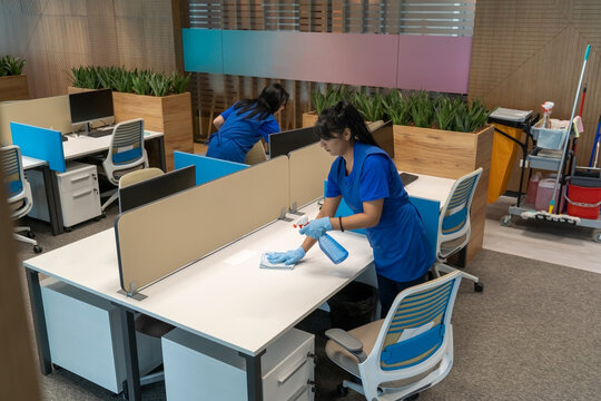 Cleaning ladies clean desks in an empty office space.Cleaning maintenance concept