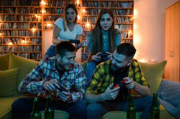 Young fun group of friends playing video games and drinking beer
