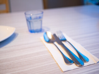 Paper towels, cutlery and glass water glasses on the dining table