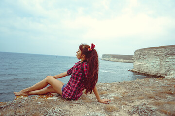 beautiful girl sitting on a rock by the sea