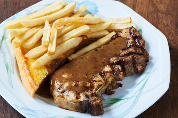 Close-up view of delicious pork chop, french fries and butter