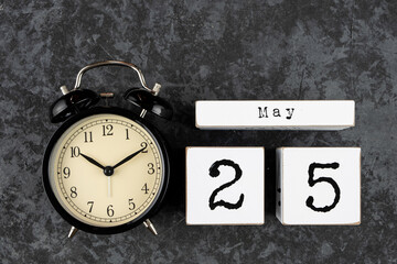 May 25th. May 25 white wooden cube calendar and alarm clock on grey grunge concrete background