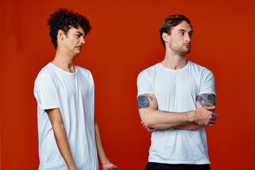 Two men in white t-shirts stand next to communication red background