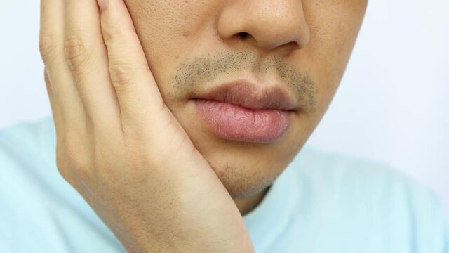 頬を押さえる男性
