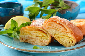 Austrian strudel with lemon and mint and with powdered sugar on a plate. Cake with orange and lemon...