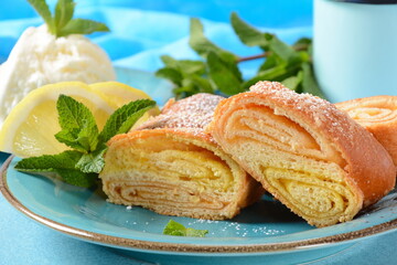 Austrian strudel with lemon and mint and with powdered sugar on a plate. Cake with orange and lemon jam