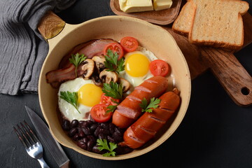 Traditional full English breakfast with bacon, fried eggs, sausages, baked beans, mushrooms.