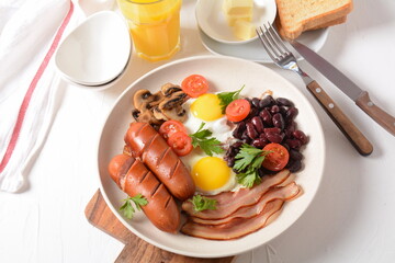 Traditional full English breakfast with bacon, fried eggs, sausages, baked beans, mushrooms.