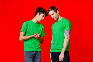 Fototapeta premium two friends in green t-shirts are standing next to tin with their hands emotions