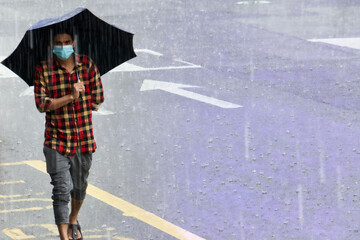 man walking in heavy rain on a street