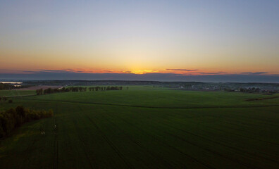 Fototapeta premium Drone view of the evening landscape at sunset with fields and clouds