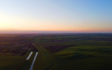 Drone view of the evening landscape at sunset with fields and clouds