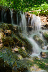 Fototapeta na wymiar Forest small waterfall on a sunny summer day