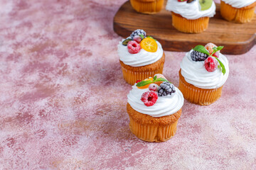 Homemade cupcakes with whipped cream and berries on top.