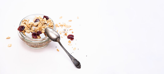 Homemade cereal granola in glass jar. Muesli with oats, nuts, chia seeds, pieces of coconut and dry berries on a light table. Modern concept of healthy eating and sustainable lifestyle.