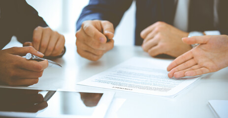 Obraz premium Group of business people and lawyers discussing contract papers sitting at the table, close-up. Successful teamwork, cooperation and agreement concepts