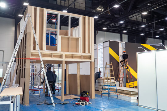 Preparation for the exhibition. Installation of structures in the exhibition hall. Workers install advertising structures before the opening of the exhibition. Construction work.