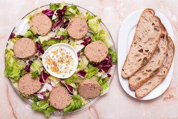 pasty disks on salad, with white sauce and toasted bread