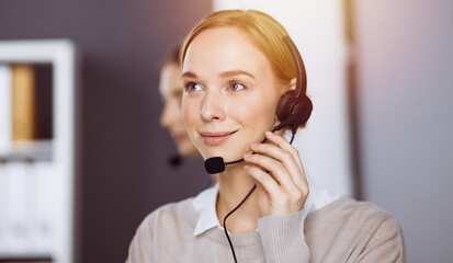 Businesswoman talking by headset in office. Call center and diverse people group in business