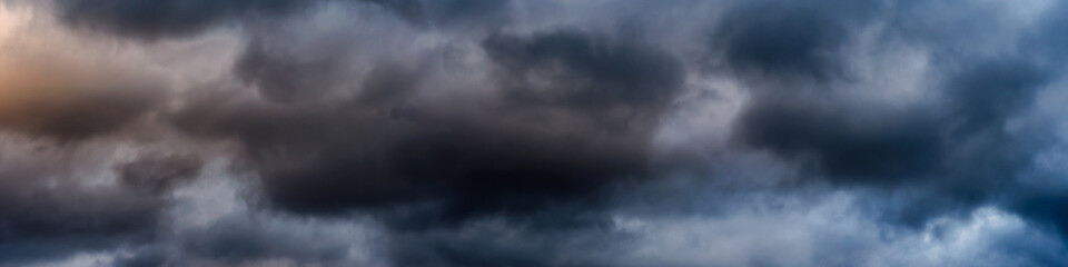 wide panoramic view of the dark dramatic stormy sky with cumulus clouds and crimson glow. sad cloudscape overcast