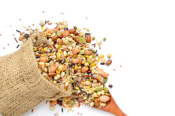 Mixed dry organic cereal and grain seeds in sack bag and wooden spoon on white background