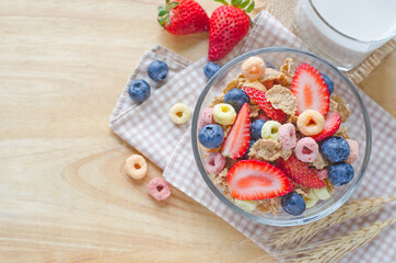 Cereal food with fresh strawberry and blueberry fruit and milk on wooden table background with copy space for adding text, for healthy breakfast meal concept