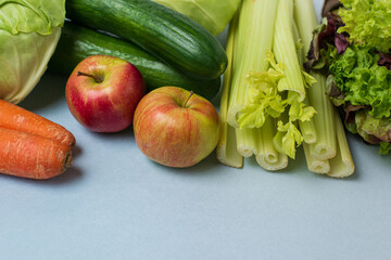 layout of vegetables on blue background: carrots, celery, cucumbers, zucchini, apples, cabbage, lettuce.  Concept of healthy eating. Vegan and vegetarian concept. Top view, place for text
