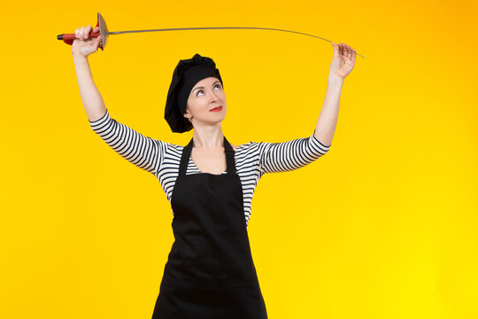 Girl with a rapier on orange background. Girl holds the sword above her head with both hands. The woman bends the epee over her head. A lady in a black apron and cap. The girl in the striped sweater.