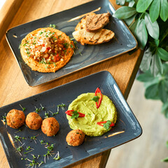 chickpea hummus and guacamole and falafel dish on blue plate on a wooden table.