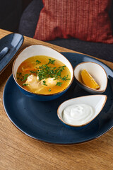 Russian homemade chicken noodle soup with dill in a white plate on a table in a restaurant