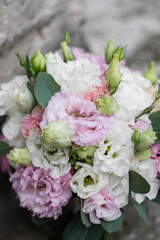 Beautiful bridal bouquet of white and pink flowers and greenery, on a gray textural background. Copy space. Lisianthus wedding bouquet.