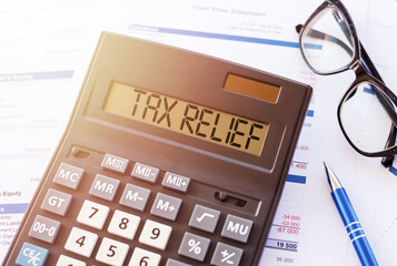 Word TAX RELIEF on the display of a calculator on financial documents.