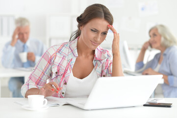 Beautiful young woman working in office, colleagues on bckground