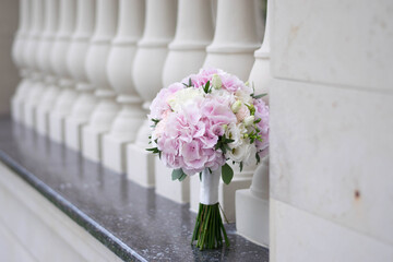 Beautiful bridal bouquet of white and pink flowers and greenery, on a gray textural background. Hydrangea wedding bouquet.