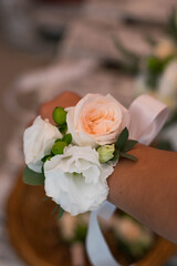 Wedding corsage on bridesmaids hand. Corsage composed of roses, lisianthus and freesia.